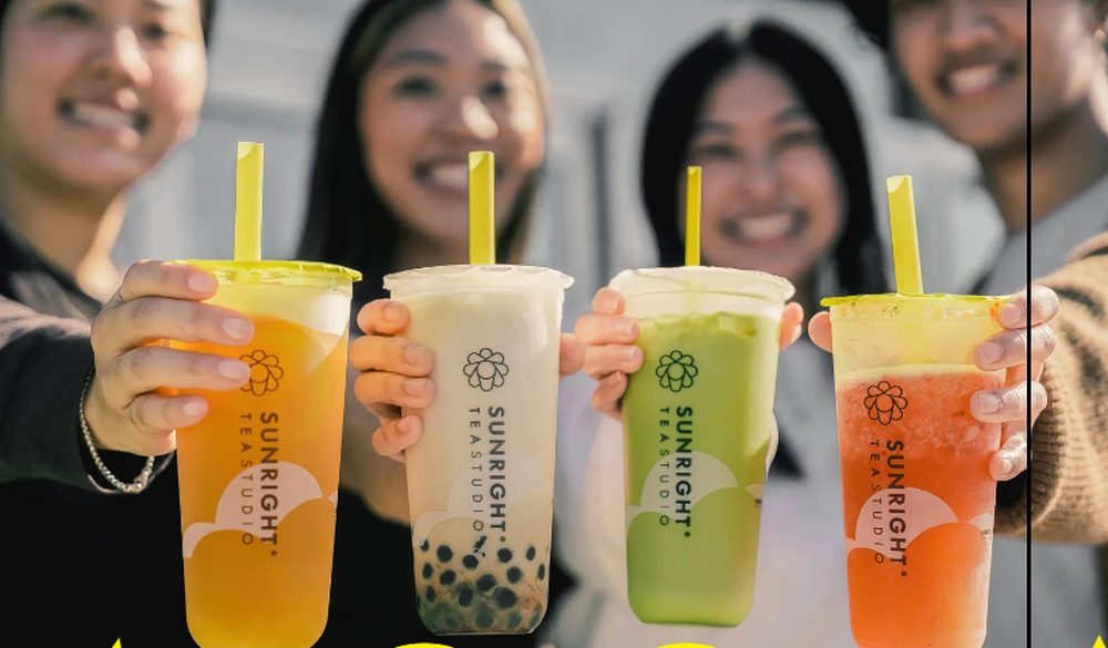 Four people holding Sunright Tea Studio boba drinks, including a brown sugar boba milk tea, in front of the store