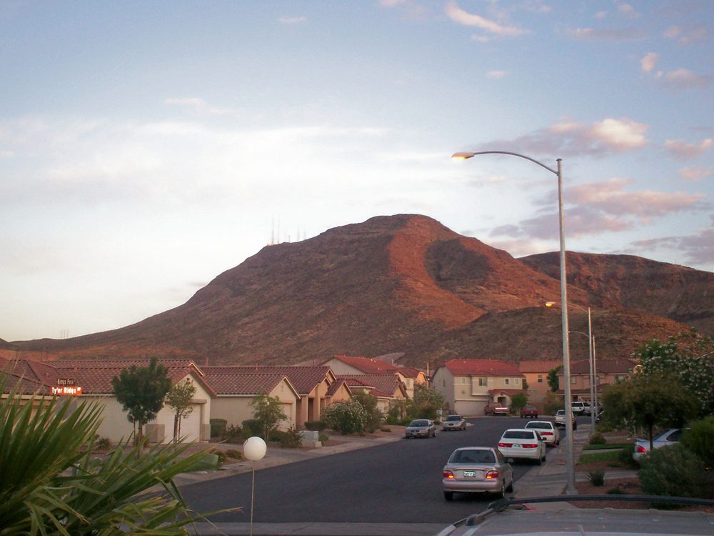 Black Mountain rising above a residential Henderson neighborhood at dusk, with communication towers visible on its summit
