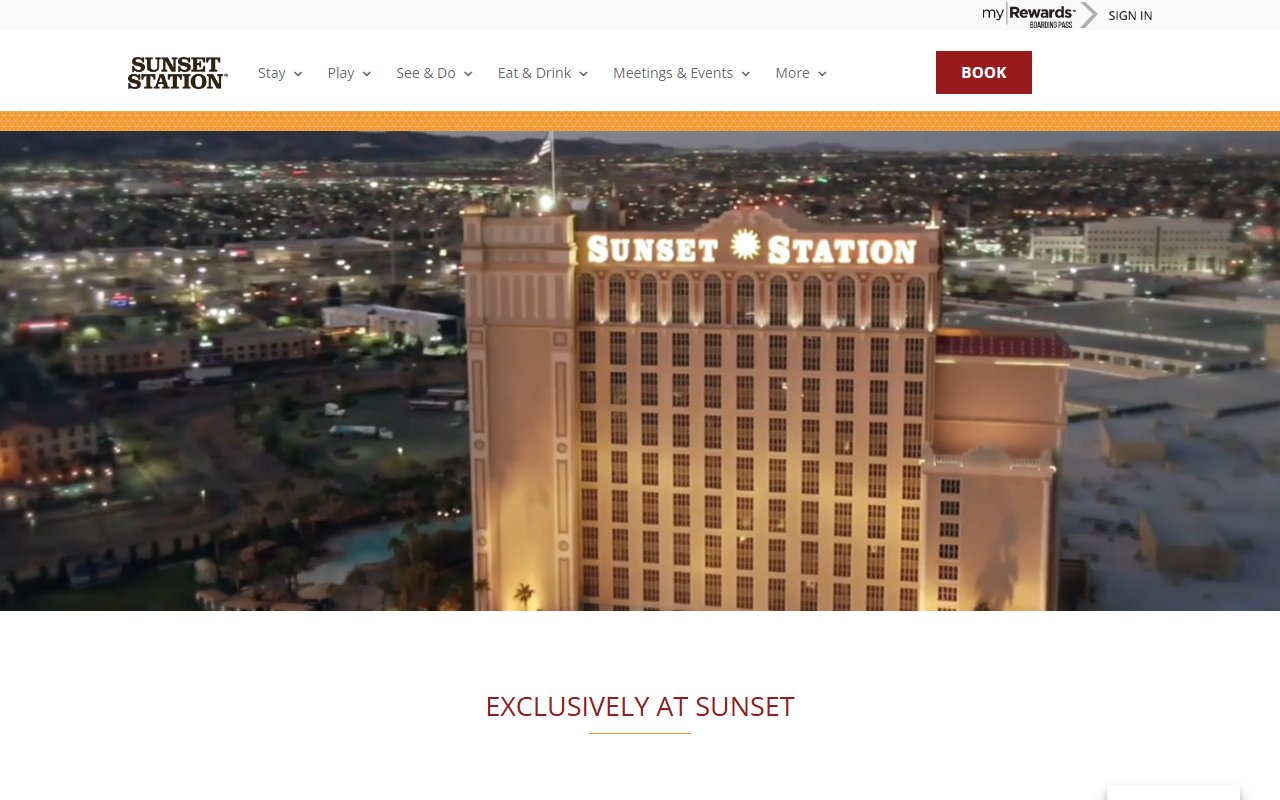 Sunset Station Hotel & Casino's illuminated hotel tower in Henderson, Nevada, seen at night from above, with the city lights spread out behind it