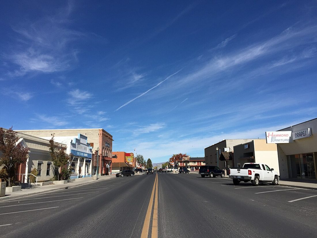 Main Street in downtown Yerington, Nevada, lined with small storefronts under a wide blue sky