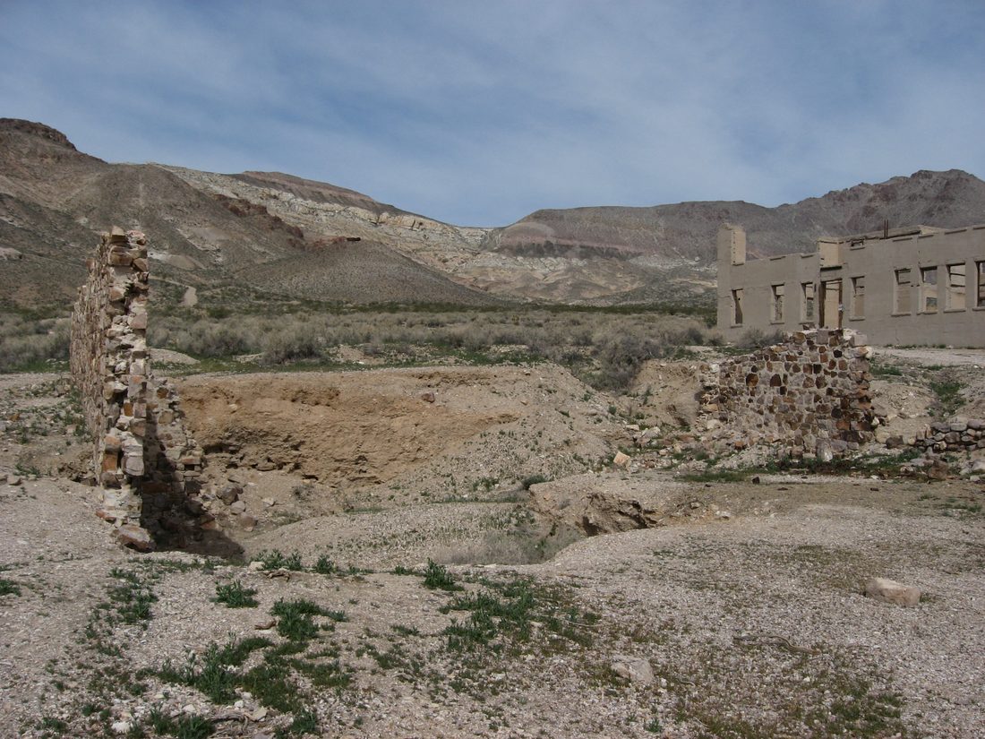 The stone ruins of a building at the Rhyolite ghost town near Beatty, Nevada, with desert mountains in the background
