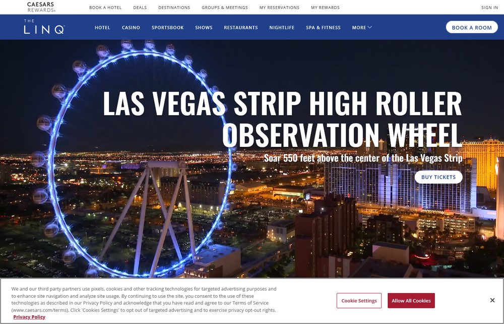 The High Roller observation wheel lit up in blue at night, with the Las Vegas Strip skyline visible behind it