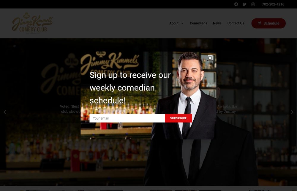 Jimmy Kimmel standing in front of the bar at Jimmy Kimmel's Comedy Club at The LINQ Promenade, wearing a black suit