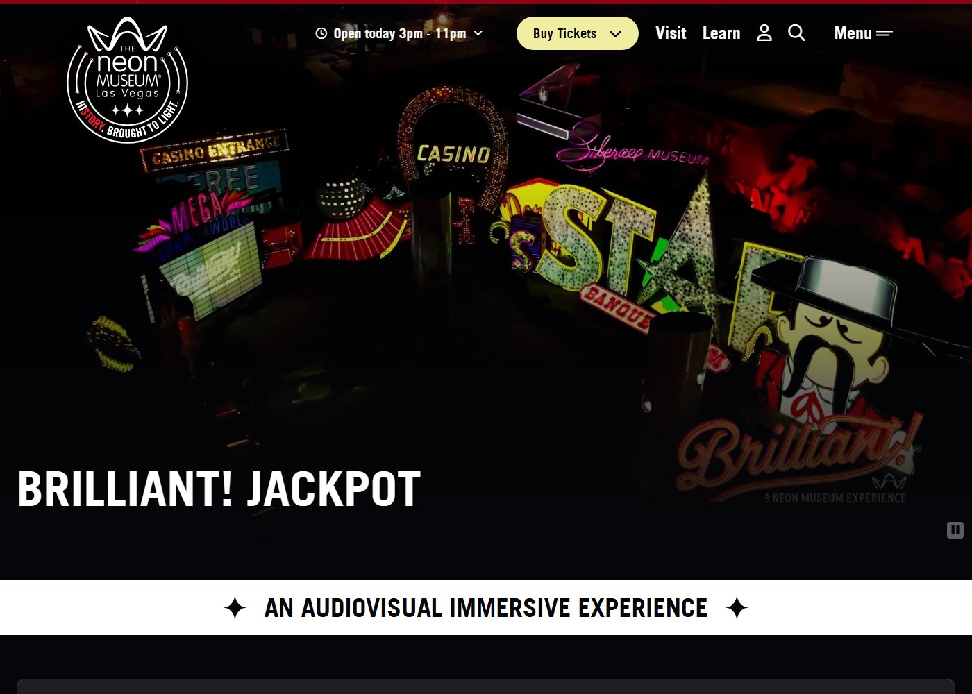 The Neon Museum's own webpage for Brilliant! Jackpot, showing projection-mapped light animating a cluster of vintage Las Vegas signs including a Hard Rock Cafe guitar and a giant star, with the Brilliant! logo overlaid