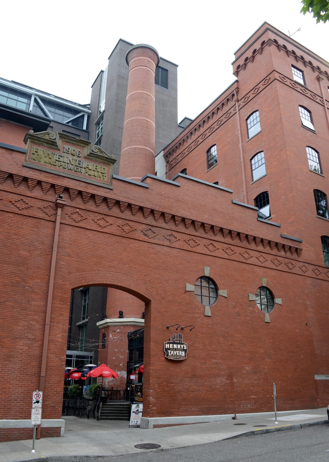 The historic red-brick Henry Weinhard Brewery Complex in Portland's Pearl District, with a tall brick smokestack and a sign reading Henry's 12th Street Tavern at street level
