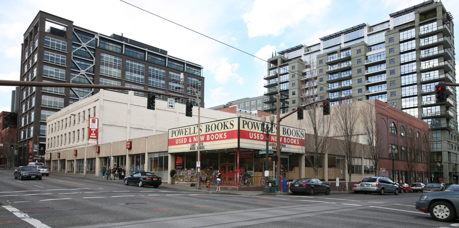 Powell's City of Books, a bookstore occupying a full city block in downtown Portland, seen from across the street with red-and-cream POWELL'S BOOKS signage wrapping around the corner