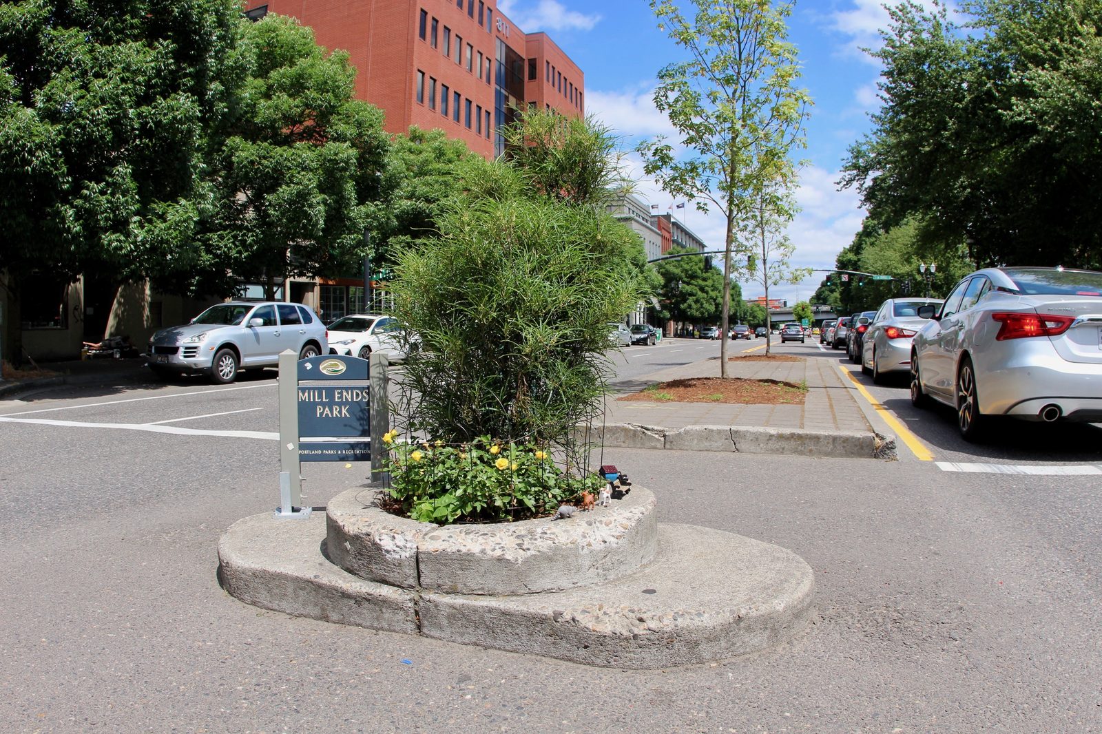 Mill Ends Park, a tiny two-foot-wide circular flower bed set into a concrete median in a downtown Portland street, marked with a small sign reading MILL ENDS PARK