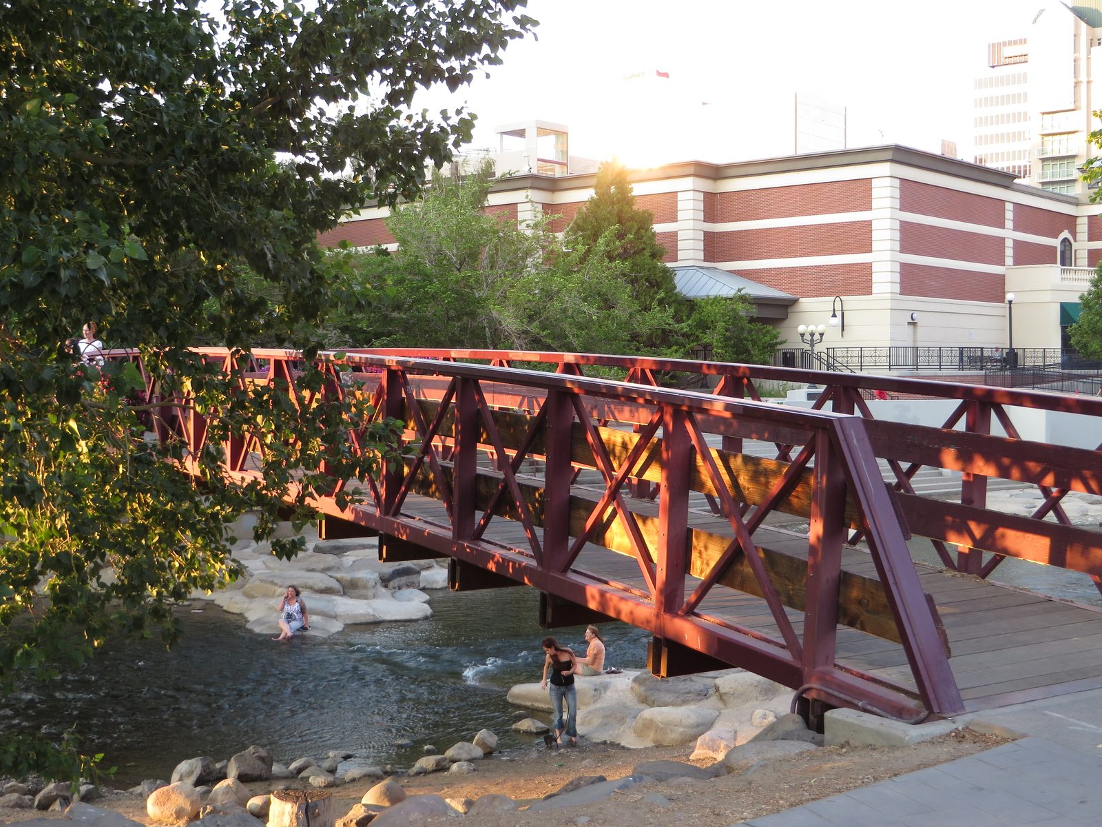 A pedestrian footbridge crossing the Truckee River Whitewater Park in downtown Reno, Nevada, with people wading in the shallow rapids below
