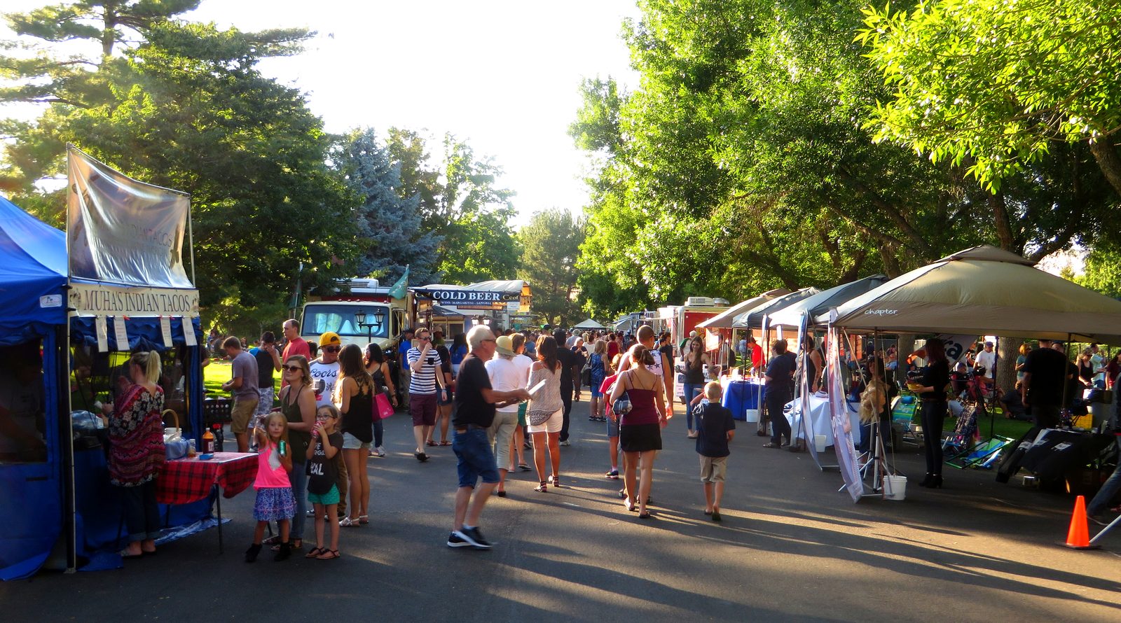 A food truck festival at Idlewild Park in Reno, Nevada, with crowds gathered around parked food trucks under trees