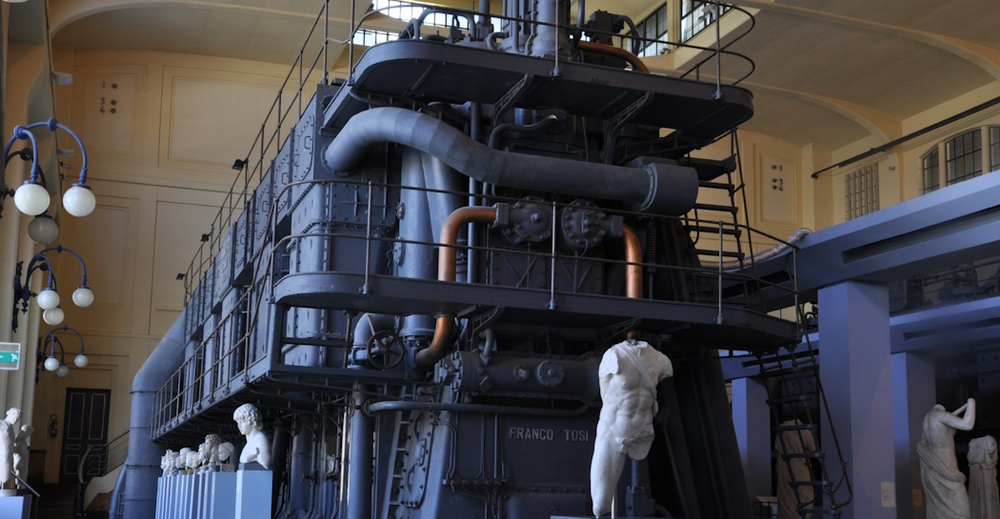 Centrale Montemartini's official site page showing a photo of classical marble statues displayed directly among the original turbines and machinery of the 1912 power plant