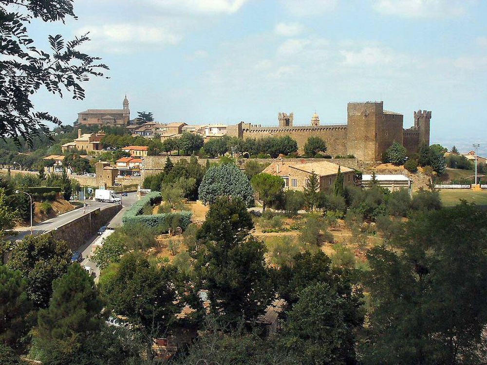 Wikipedia's Montalcino article showing a photo of cypress trees on a hillside at sunset overlooking the Val d'Orcia near the town