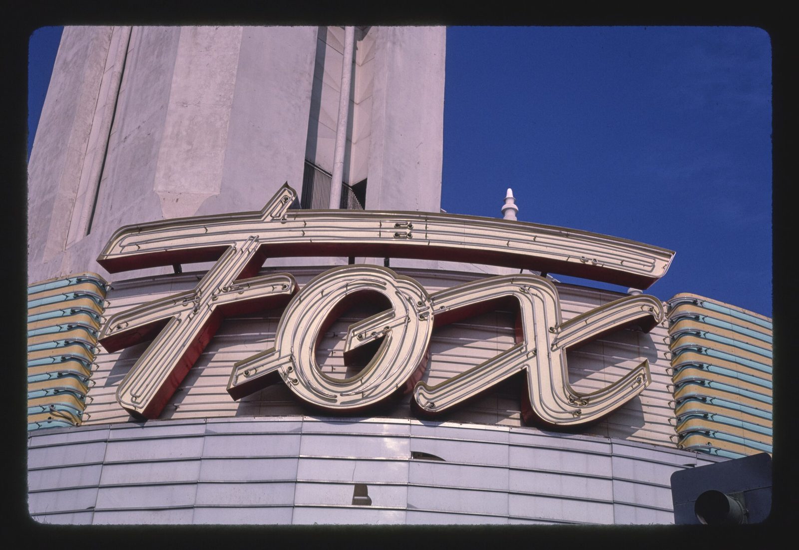 The illuminated Fox neon sign on the tower of the Fox Theater in downtown Bakersfield, California, against a blue sky