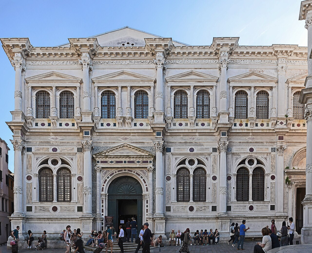 Wikipedia's Scuola Grande di San Rocco article showing a photo of the building's facade and a gilded, painted upper hall ceiling covered entirely in Tintoretto canvases